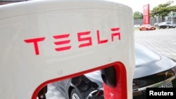 FILE - A Tesla electric car is charged by a supercharger at its showroom in Taipei, Taiwan, Aug. 11, 2017.