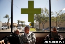 In this February 19, 2019 photo, Kay Nelson, left, and Bryan Grode, retried seniors from Laguna Woods Village, talk in the lobby of Bud and Bloom cannabis dispensary while waiting for free transportation to arrive in Santa Ana, California.