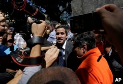 Supporters of opposition leader Juan Guaido and the press gather around him as he leaves a public plaza where he spoke in Caracas, Venezuela, Friday, Jan. 25, 2019.