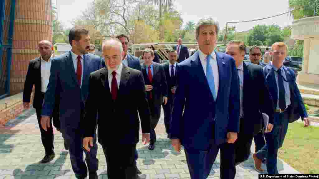 Menteri Luar Negeri AS John Kerry berjalan bersama Menteri Luar Negeri Irak al-Eshaiker al-Jaafari di tempat tinggalnya di Baghdad, Irak (8/4).