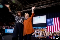 First lady Michelle Obama and Democratic presidential candidate Hillary Clinton wave together after speaking at a campaign rally at Wake Forest University in Winston-Salem, N.C., Oct. 27, 2016.