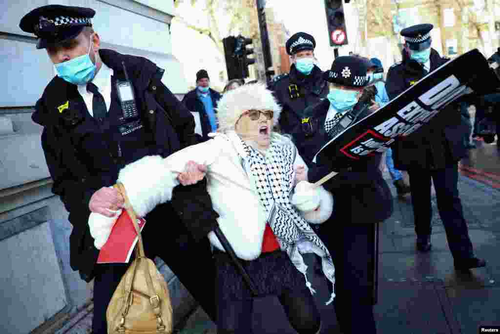 Police officers detain a woman holding a placard outside the Westminster Magistrates Court as Julian Assange&#39;s lawyers seek bail for their client in London.