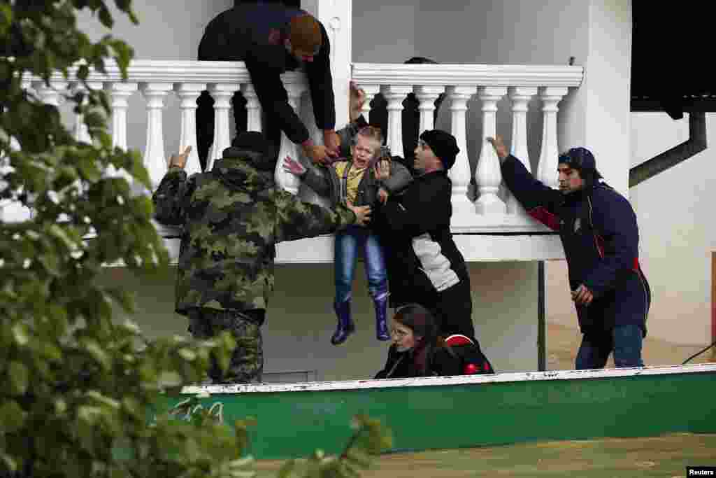 Tentara angkatan darat Serbia mengevakuasi seorang anak laki-laki dari sebuah rumah yang kebanjiran di ktoa Obrenovac, barat daya Belgrad, Serbia (17/5).&nbsp;(Reuters/Marko Djurica)