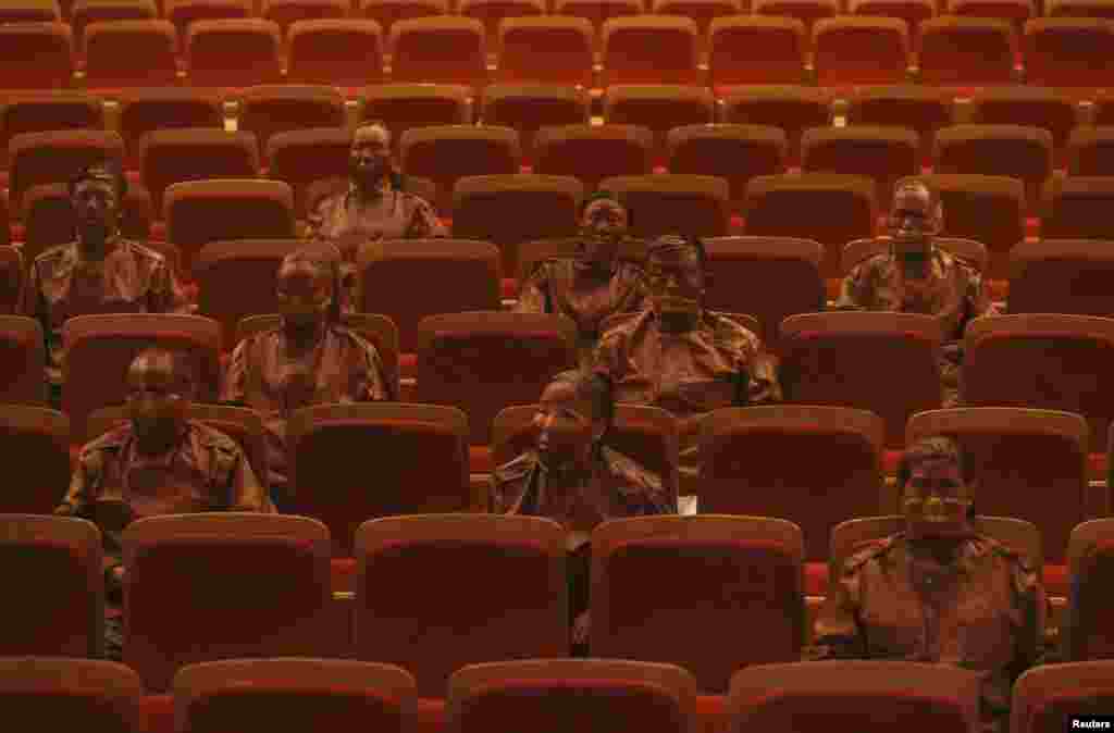 Artist Liu Bolin (3rd row, R) and other participants, painted as part of a project called &quot;Red Theatre&quot;, make themselves look exactly the same as the seats in a theatre, in Beijing, China.