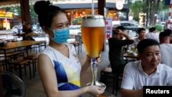 A woman serves beer at a restaurant after the govenment eased nationwide lockdown during the coronavirus disease (COVID-19) outbreak in Hanoi, Vietnam April 29, 2020. (REUTERS/Kham)