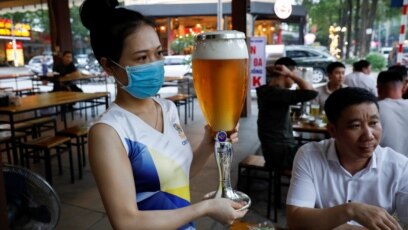 Một phụ nữ phục vụ bia hơi ở một nhà hàng ở Hà Nội sau khi chính phủ Việt Nam dỡ bỏ cách ly toàn xã hội trong thời gian bùng phát dịch virus corona hôm 29/4. Nhà nước do Đảng Cộng sản nắm quyền được ca ngợi thành công trong chống 'giặc' COVID-19 nhưng ít được thế giới biết tới.