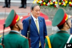 Japanese Prime Minister Yoshihide Suga reviews an honor guard at the Presidential Palace in Hanoi, Vietnam Monday, Oct. 19, 2020. Suga is on an official visit to Vietnam. (AP Photo/Minh Hoang, Pool)