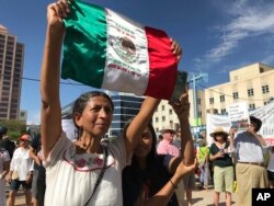 Margarita Perez of Albuquerque, with her daughter by her side, holds up a Mexican flag during a protest on Civic Plaza in Albuquerque, N.M., June 30, 2018. Perez was among thousands who gathered on the plaza to voice their opposition to U.S. immigration policies and President Donald Trump.