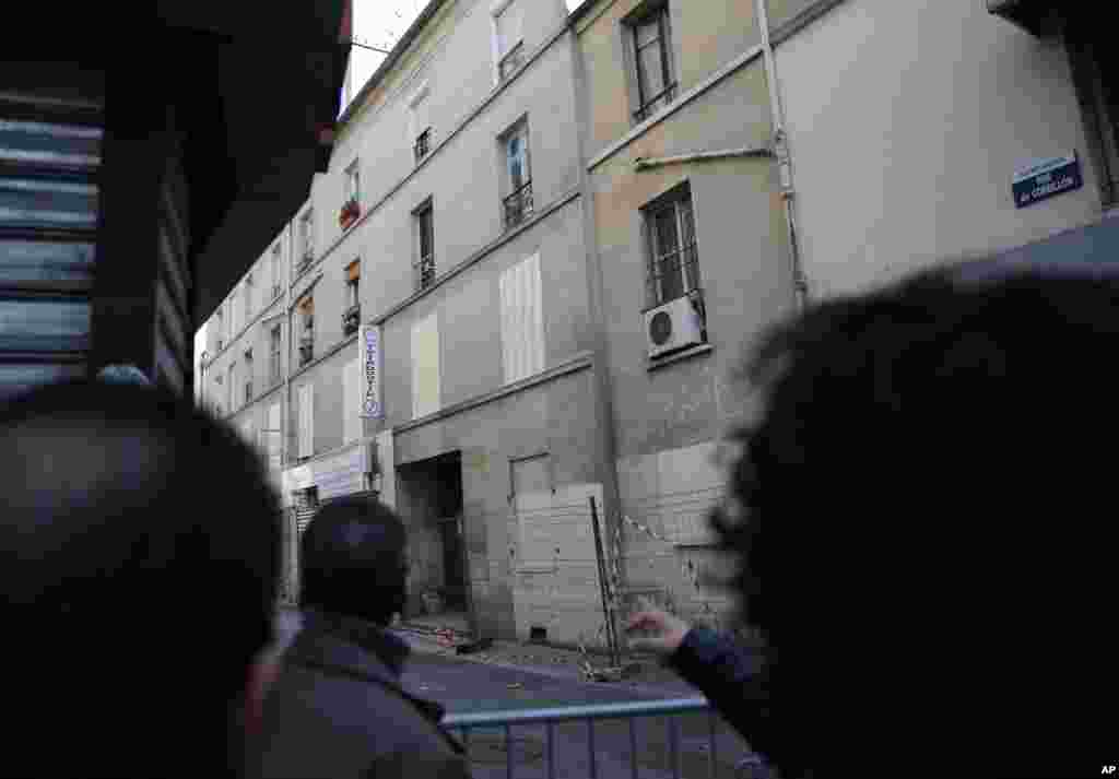 Residents watch the building of last Wednesday&#39;s raid in Saint-Denis, outside Paris.