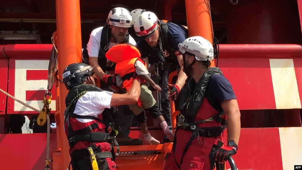 Kru kapal penyelamat 'Ocean Viking' yang dioperasikan LSM Perancis, SOS Mediterranee dan Medecins sans Frontieres (MSF), membantu seorang anak migran Libya naik ke kapal dari perahu karet, 9 Agustus 2019. (Foto: AFP)