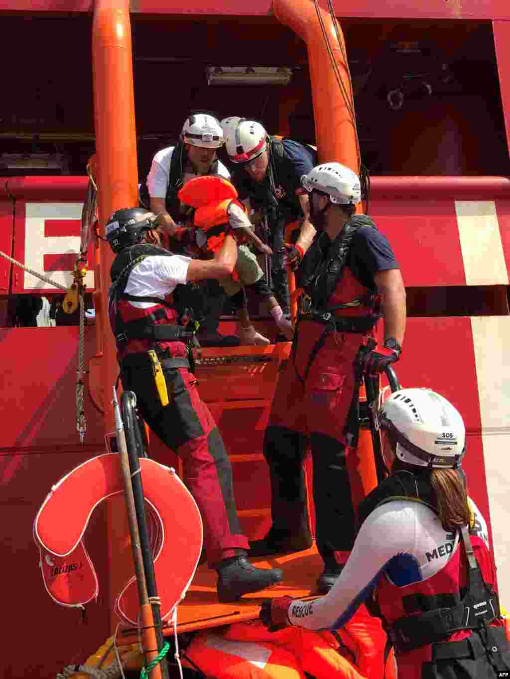 Crew members of the &#39;Ocean Viking&#39; rescue ship, operated by French NGOs SOS Mediterranee and Medecins sans Frontieres (MSF), help a child climb on board from an inflatable rescue dinghy, during their first rescue operation in the Mediterranean Sea.