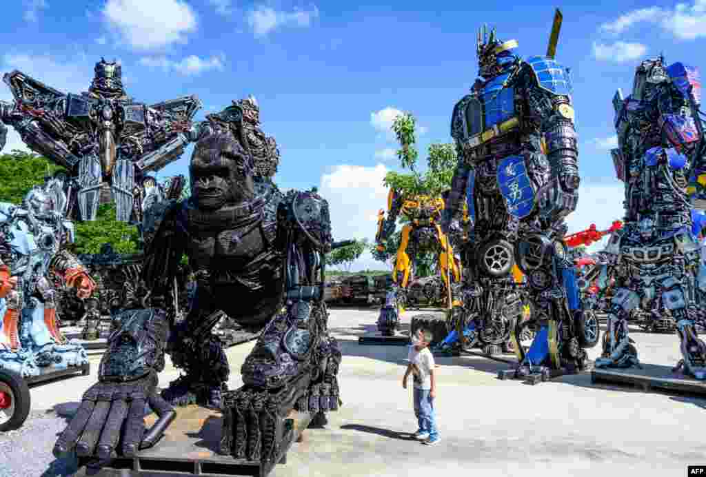 A child looks at a figure of King Kong in front of life-sized sculptures of characters from the &quot;Transformers&quot; film franchise, all made of scrap metal parts, at the Ban Hun Lek museum in Ang Thong, some 100km north of Bangkok, Thailand, July 18, 2020.