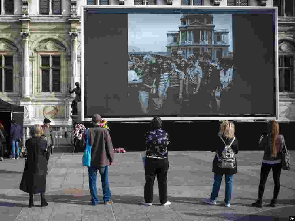 People watch former French President Jacques Chirac on a large screen in Paris.