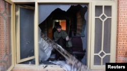 An Afghan man removes burning items from the house of an Afghan member of parliament that was attacked by Taliban, Dec. 21, 2016, in Kabul, Afghanistan.