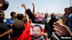 A supporter of former president Hosni Mubarak holds his poster to celebrate as she waits for his release in front of the main gate of Tora prison on the outskirts of Cairo, August 22, 2013. 