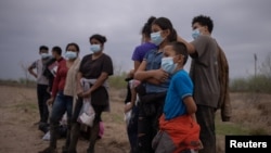 Khoảng 12 trẻ em di dân không có người lớn đi kèm từ Trung Mỹ bị lực lượng Tuần tra Biên giới Hoa Kỳ giữ lại sau khi băng qua sông Rio Grande vào Mỹ từ Mexico, ngày 14 tháng 3, 2021.
