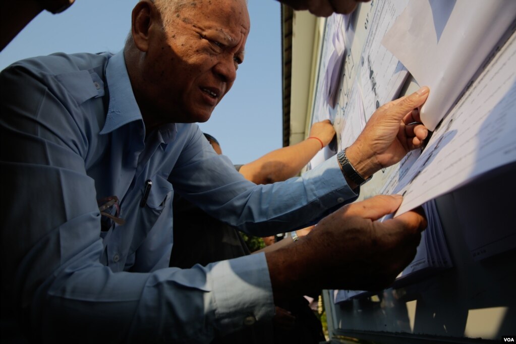 ក្រុមប្រឹក្សាសង្កាត់ម្នាក់កំពុងស្វែងរកឈ្មោះរបស់ខ្លួនក្នុងមុននឹងចូលទៅបោះឆ្នោតព្រឹទ្ធសភា កាលពីថ្ងៃទី២៥ ខែកុម្ភៈ ឆ្នាំ២០១៨ នៅមណ្ឌលបោះឆ្នោតមួយ ក្នុងបរិវេណវិទ្យាល័យហ៊ុនសែនប៊ុនរ៉ានីវត្តភ្នំ រាជធានីភ្នំពេញ។ (អូន ឆេងប៉រ/VOA)