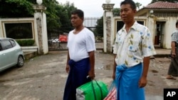 Burmese political prisoners Win Thaw (L) and Win Hla (R) stand outside the entrance of the Insein Prison upon their release after receiving amnesty from Burmese President Thein Sein, in Rangoon, Burma, July 23, 2013.