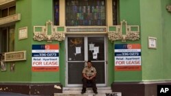 FILE - A private security guard sits in front of a closed down business in the colonial district of Old San Juan, Puerto Rico, Sunday, Aug. 2, 2015. Puerto Rico's government has some $70 billion in debt, $2 billion of which is due Friday.