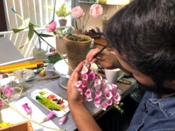 Seorang desainer melukis bunga yang terbuat dari kertas di studionya di New York City, AS, 29 Agustus 2019. (Foto: REUTERS/Roselle Chen)