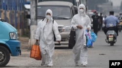 Nhân viên mặc đồ bảo hộ đi bộ trên một con đường gần chợ Tân Phát Địa ở Bắc Kinh, ngày 13 tháng 6, 2020.