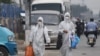 Duas mulheres vestidas com equipamento de proteção junto ao mercado Xinfadi, em Pequim, encerrado devido a novos casos de Covid-19