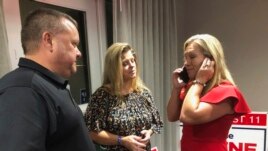 Supporters stand with construction executive Marjorie Taylor Greene, right, as she's on the phone, late Tuesday, Aug. 11, 2020, in Rome, Ga.