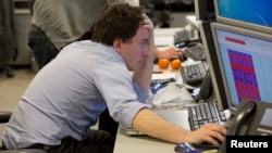 A trader looks at his screen on the IG Group trading floor in London March 18, 2013. The surprise decision by eurozone leaders to partially fund a bailout of Cyprus by taxing bank deposits sent shockwaves through financial markets on Monday.