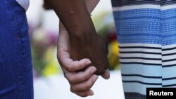 Mourners hold hands outside the Emanuel African Methodist Episcopal Church in Charleston, South Carolina, June 18, 2015.