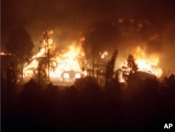 FILE - Homes in west Los Alamos are engulfed in flames as a controlled burn set by the National Park Service last week to clear brush at nearby Bandelier National Monument spread into the town of Los Alamos, May 10, 2000.