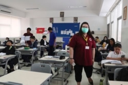 Seorang guru mengenakan masker wajah di kelas di Jakarta Nanyang School di Serpong, 3 Maret 2020, saat Indonesia melaporkan kasus pertama virus corona. (Foto: AP)
