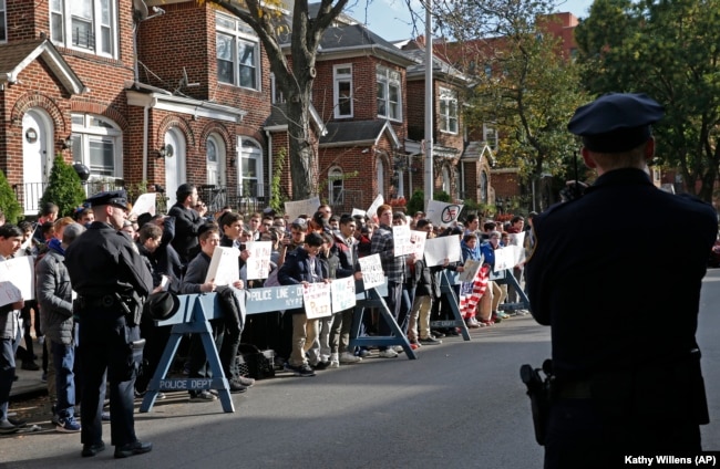 FILE - Police stand guard as students from Rambam Mesivta Orthodox Jewish high school protest across the street from the home of a former Nazi prison camp guard, in New York, Nov. 9, 2017.