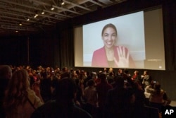 Rep. Alexandria Ocasio-Cortez, D-N.Y. waves as she appears on screen via videoconference for a question and answer session after the premiere screening of the documentary "Knock Down the House," Jan. 27, 2019,
