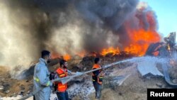 Des pompiers palestiniens éteignent un incendie dans un entrepôt de peinture qui, selon des témoins, a été touché par des frappes israéliennes à Rafah, dans le sud de la bande de Gaza, le 18 mai 2021.