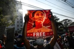 (FILES) In this file photo taken on February 15, 2021, a protester holds up a poster featuring Aung San Suu Kyi during a demonstration against the military coup at in front of the Central Bank of Myanmar in Yangon. - Myanmar's military seized power on Feb