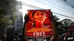 Seorang pengunjuk rasa memegang poster Aung San Suu Kyi selama demonstrasi menentang kudeta militer di depan Bank Sentral Myanmar di Yangon, 15 Februari 2021. (Foto: AFP)