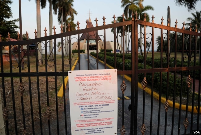 A sign hanging on a locked gate in front of the Ermita de la Caridad church in Miami indicates that the church is closed during the new coronavirus pandemic, Thursday, April 9, 2020.