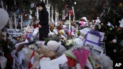 Jeanne Walker walks through an overflowing memorial to the shooting victims, Newtown, Connecticut, December 20, 2012. 