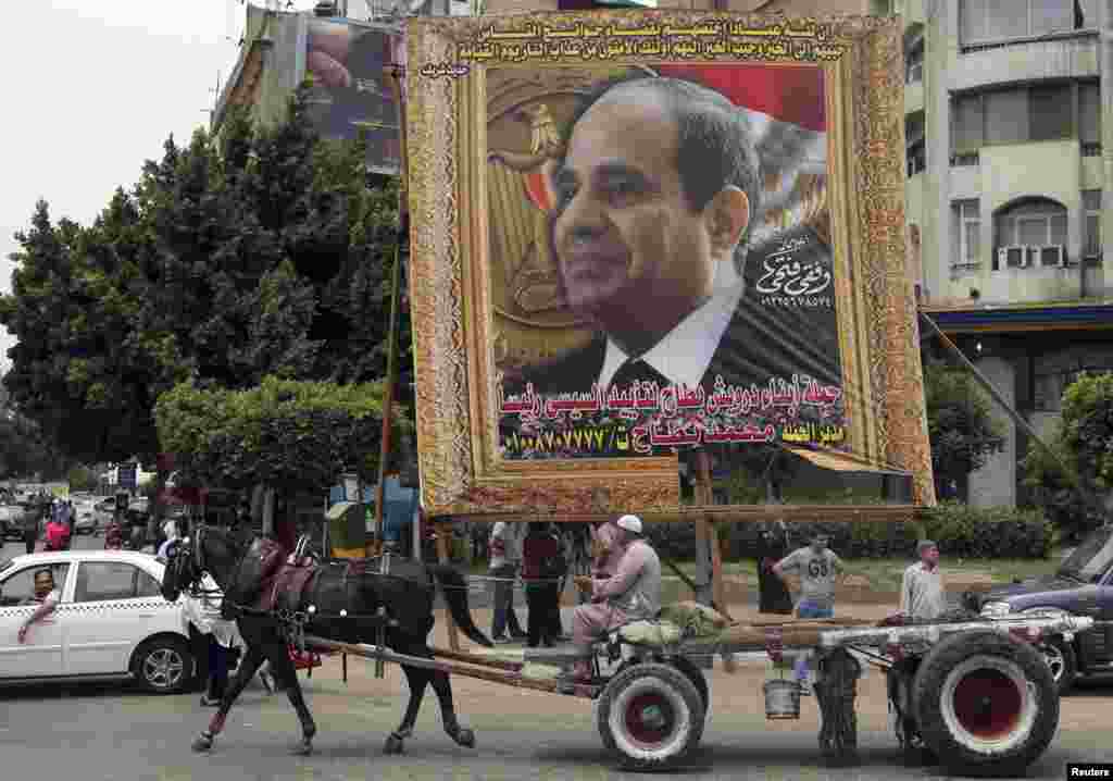 A man on a horse cart rides past a huge banner of former army chief Abdel-Fattah el-Sissi, in downtown Cairo, May 6, 2014.