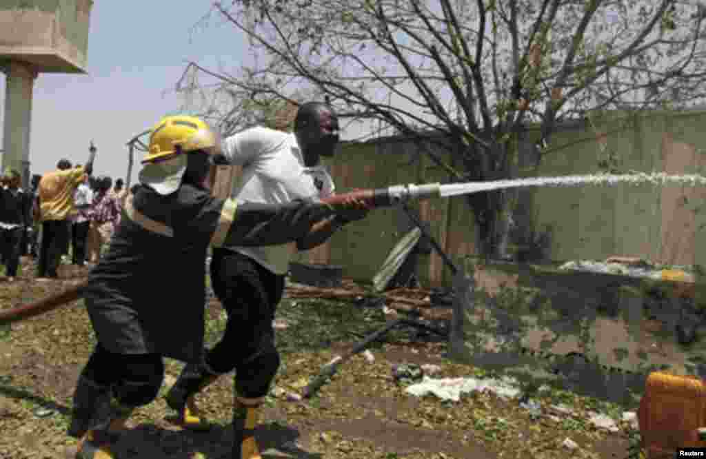 Firefighters drag a hose through the damaged building of Nigerian newspaper This Day after a bomb blast in its premises in Abuja April 26, 2012.