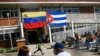 Frente a sendas banderas de Venezuela y Cuba, un chico corre mientras un grupo de personas espera recibir su vacuna contra el COVID-19, en la barriada Ciudad Tiuna, en Caracas, el 29 de junio de 2021.