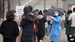 A medical worker holds a sign for visitors to prepare for the coronavirus tests at a temporary screening clinic for coronavirus in Seoul, South Korea on Dec. 10, 2021. 