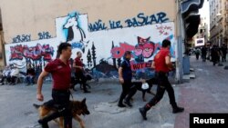 Police officers with dogs chase LGBT rights activists as they try to gather for a pride parade, which was banned by the governorship, in central Istanbul, Turkey, June 25, 2017.