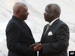 FILE - Mozambique President Arnando Guebuza, left, and former Renamo rebel leader Afonso Dhlakama, right, shake hands after signing a peace accord, Sept. 5, 2014.