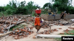 지난 8일 인도 북동부 아가르탈라에서 모래 폭풍이 강타한 후, 여성이 소지품들을 챙겨 부서진 집 사이로 걷고 있다. 