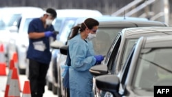 Health officials collect COVID-19 swab tests at a drive-through testing site on Bondi beach in Sydney on Dec. 15, 2021, as rapidly-growing Omicron and Delta clusters brought more than 2,700 new cases nationally. 