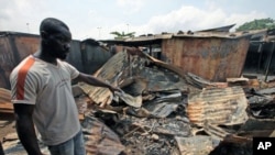 A man points to a burnt shop near Williamsville after a clash between Ivorian security forces and pro-Outtara fighters in Abidjan, March 15, 2011