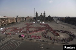 FILE - Cyclists gather to form a shape of a bicycle with the aim of promoting cycling as a mode of transport and to commemorate Bicycle Day, which is celebrated April 19 annually, at Zocalo square in Mexico City, Mexico, April 10, 2016.