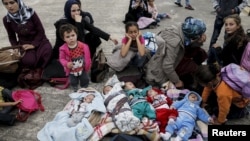 Five Syrian babies, three of them triplets (L to C), lie in blankets among their relatives as they arrive with other refugees and migrants aboard the passenger ferries Blue Star Patmos and Eleftherios Venizelos from the islands of Lesbos and Chios at the 