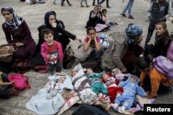 FILE - Five Syrian babies, three of them triplets, left to center, lie in blankets among their relatives as they arrive with other refugees and migrants aboard the passenger ferries Blue Star Patmos and Eleftherios Venizelos from the islands of Lesbos and Chios at the